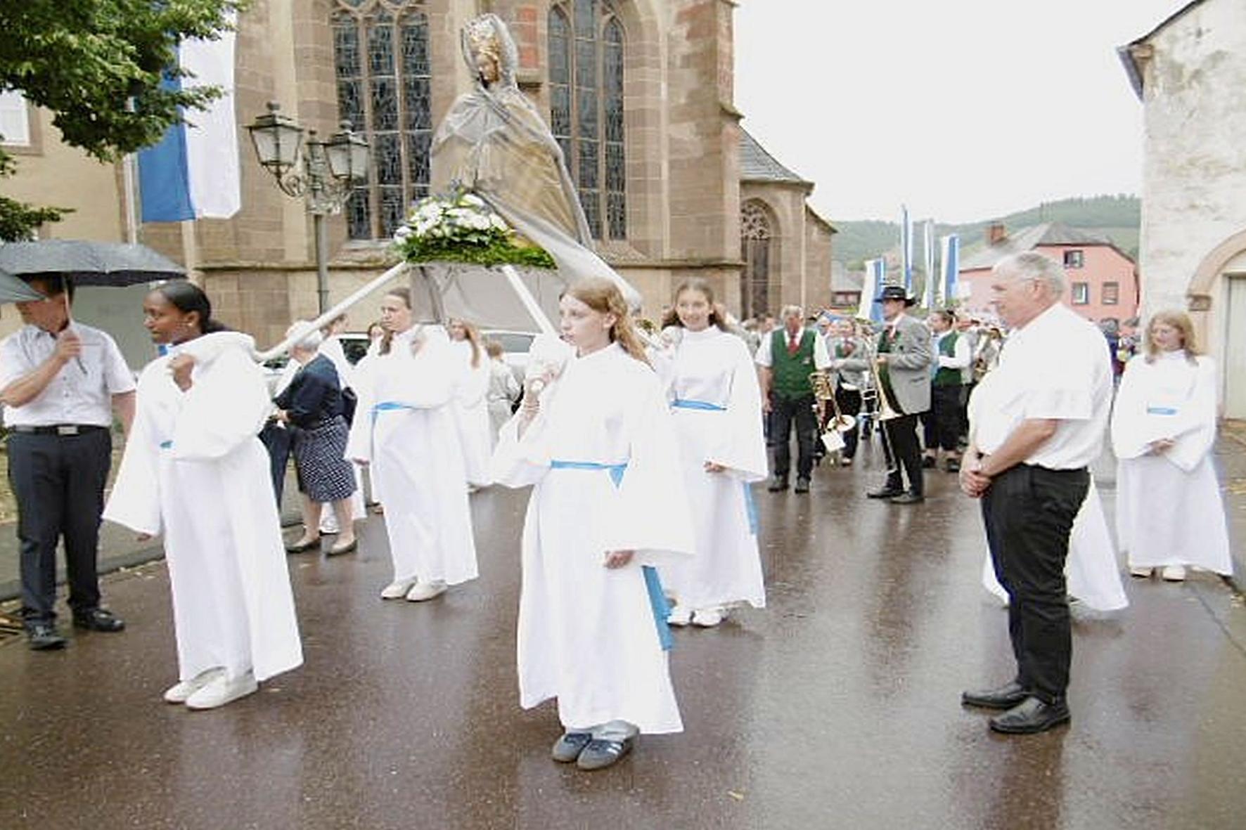 Weiß gekleidete Mädchen tragen eine Marienfigur