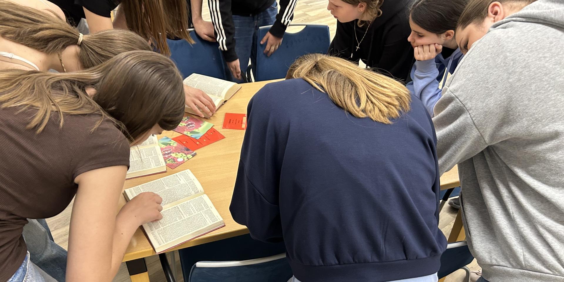 Jugendliche beim durchsuchen von Textstellen in Büchern.