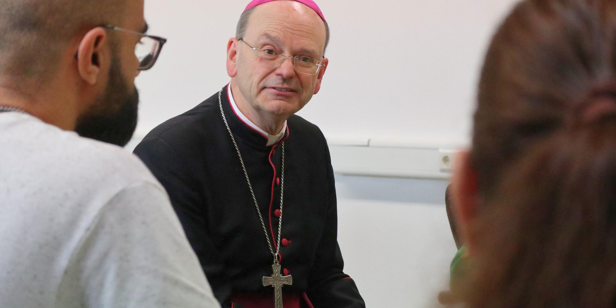 Weihbischof Robert Brahm tauscht sich mit Teilnehmenden eines Sprachkurses des Caritasverbands Rhein-Wied-Sieg in Betzdorf aus.