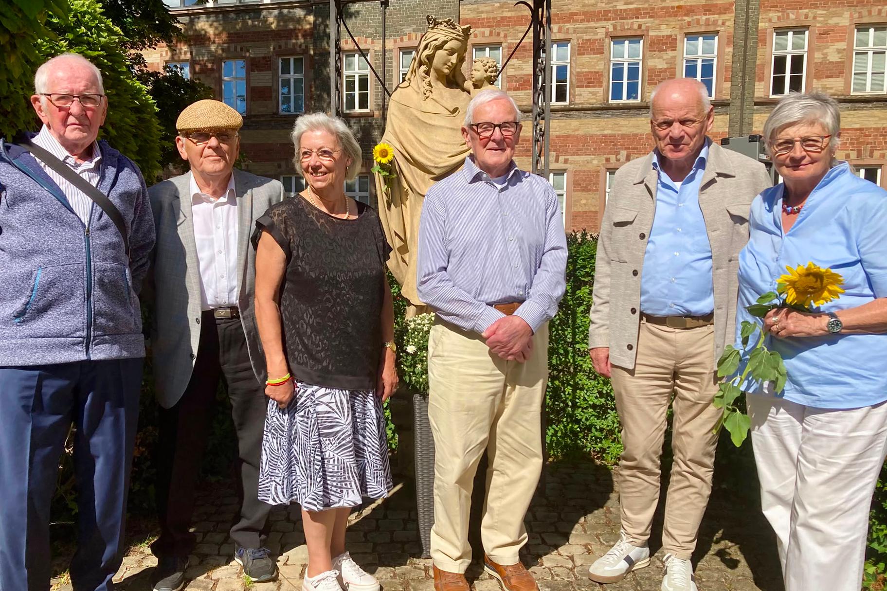 Sechs Personen stehen vor einer Statue für ein Gruppenbild zusammen