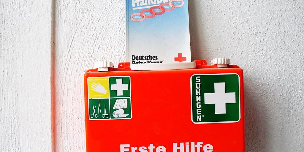 An einer weißen Wand hängt ein Erste-Hilfe-Kasten