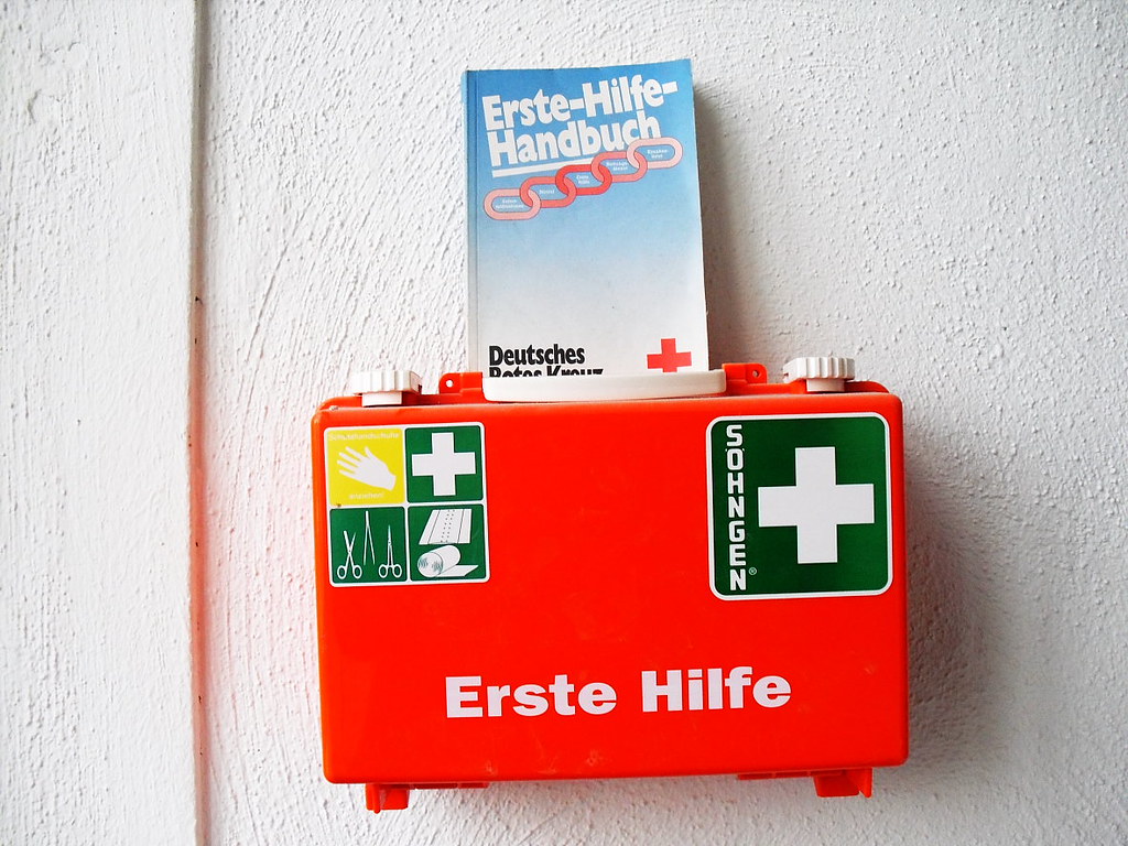 An einer weißen Wand hängt ein Erste-Hilfe-Kasten