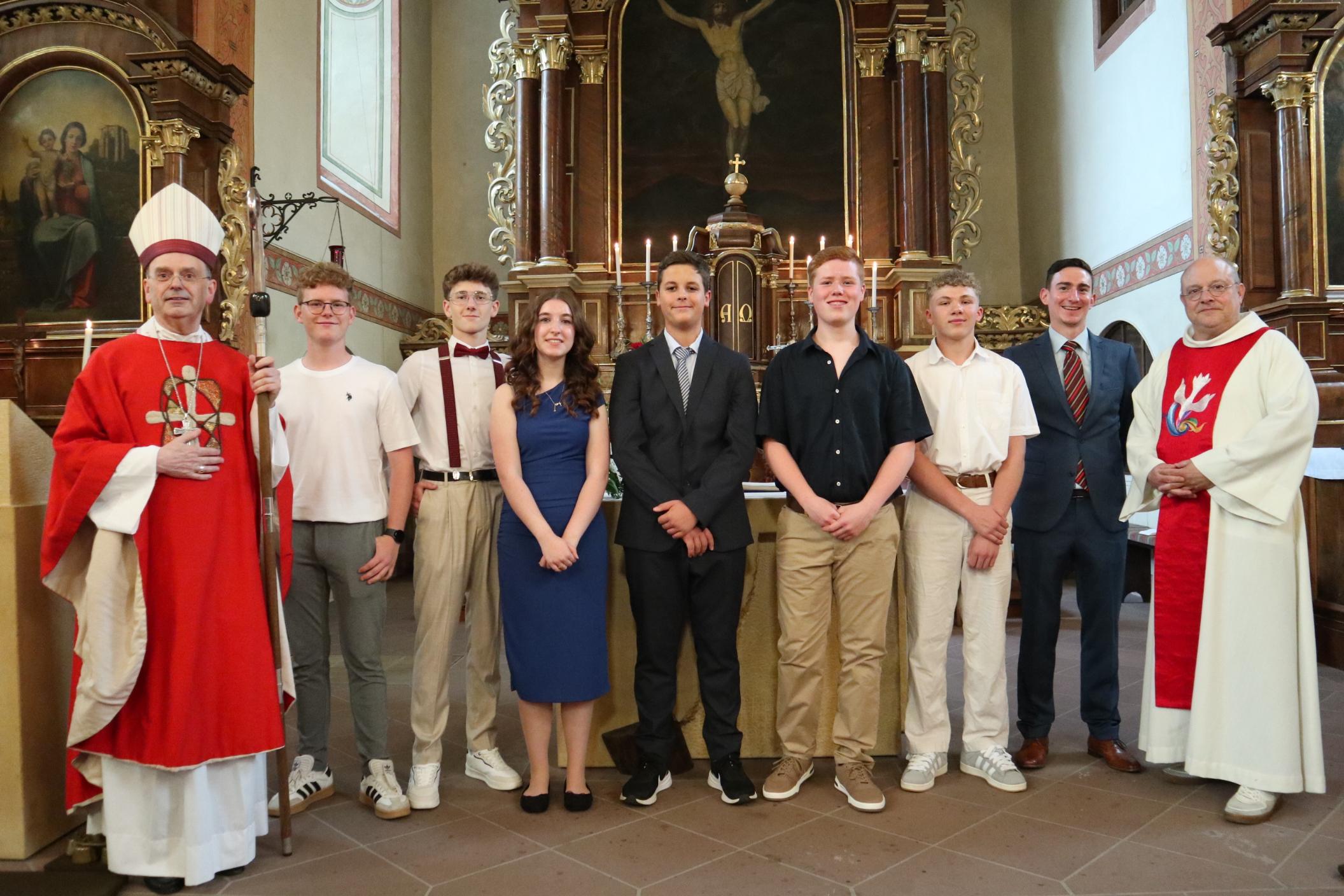 Weihbischof Robert Brahm (links), Pfarrer Michael Knipp (rechts) und Pastoralreferent Tobias Petry (Zweiter v. rechts) gratulieren den jungen Menschen in der Kirche St. Nikolaus in Bacharach zu ihrer Firmung.