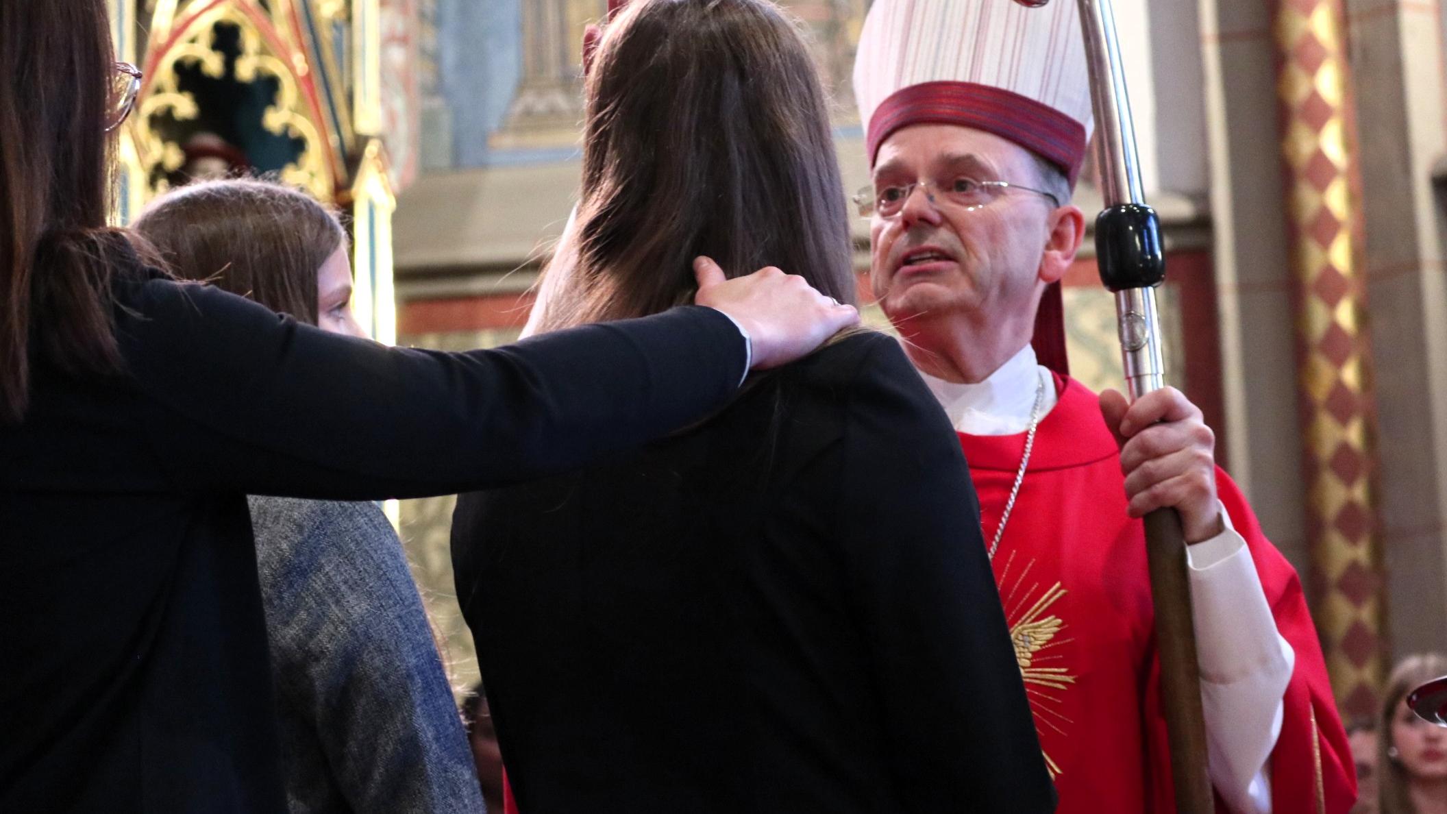 Weihbischof Brahm zeichnet ein Kreuz mit Chrisam-Öl auf die Stirn der Jugendlichen.