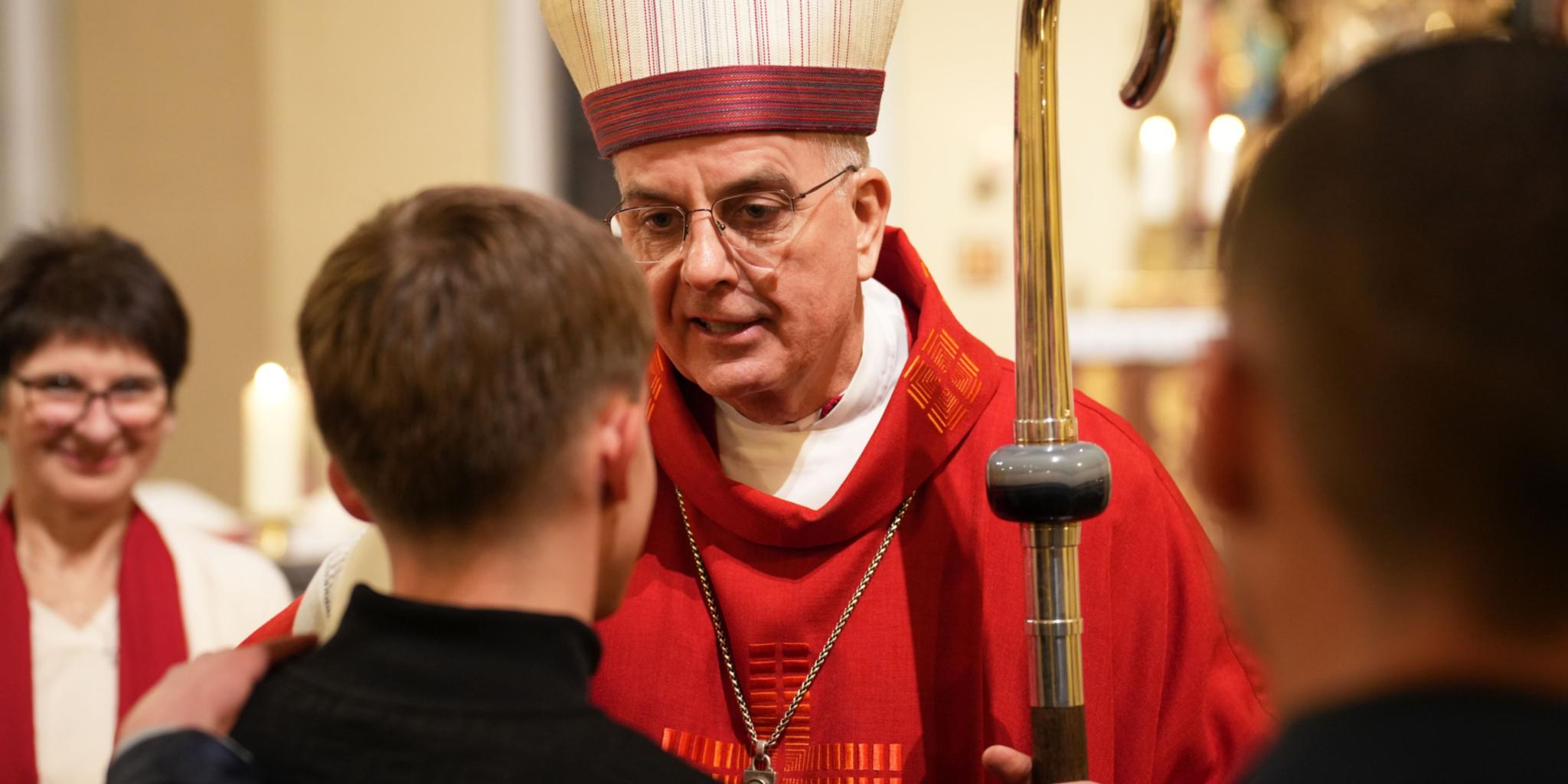 Weihbischof Peters spendet den jungen Menschen in der Kirche St. Maximin in Bettingen das Firmsakrament.