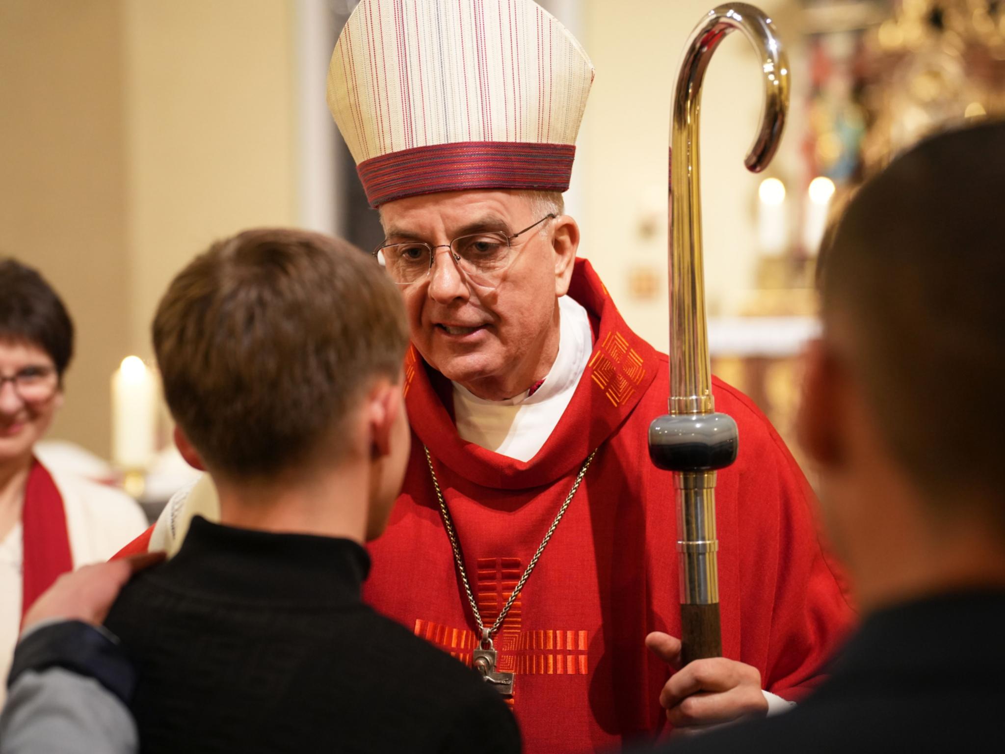 Weihbischof Peters spendet den jungen Menschen in der Kirche St. Maximin in Bettingen das Firmsakrament.