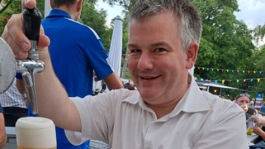 Ein Mann zapft Bier an einem Ausschankstand bei einer Veranstaltung im Freien.