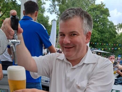 Ein Mann zapft Bier an einem Ausschankstand bei einer Veranstaltung im Freien.