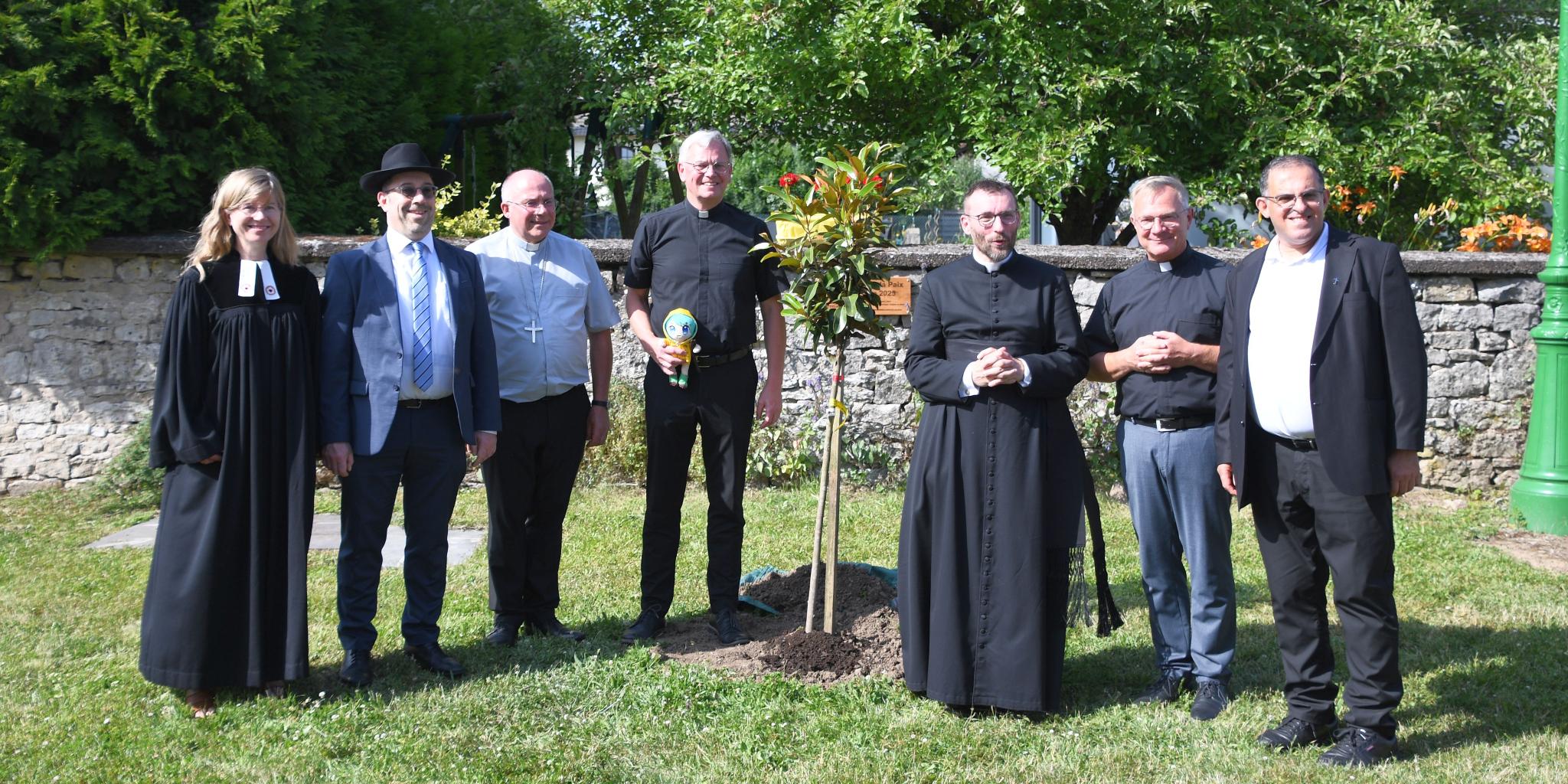Cosima Hoffmann, Ariel Wertenschlag, Erzbischo Philippe Ballot, Generalvikar Ulrich von Plettenberg, David Chaudey, Markus Wirth und Samih Raad vor dem frisch gepflanzten Friedensbaum.