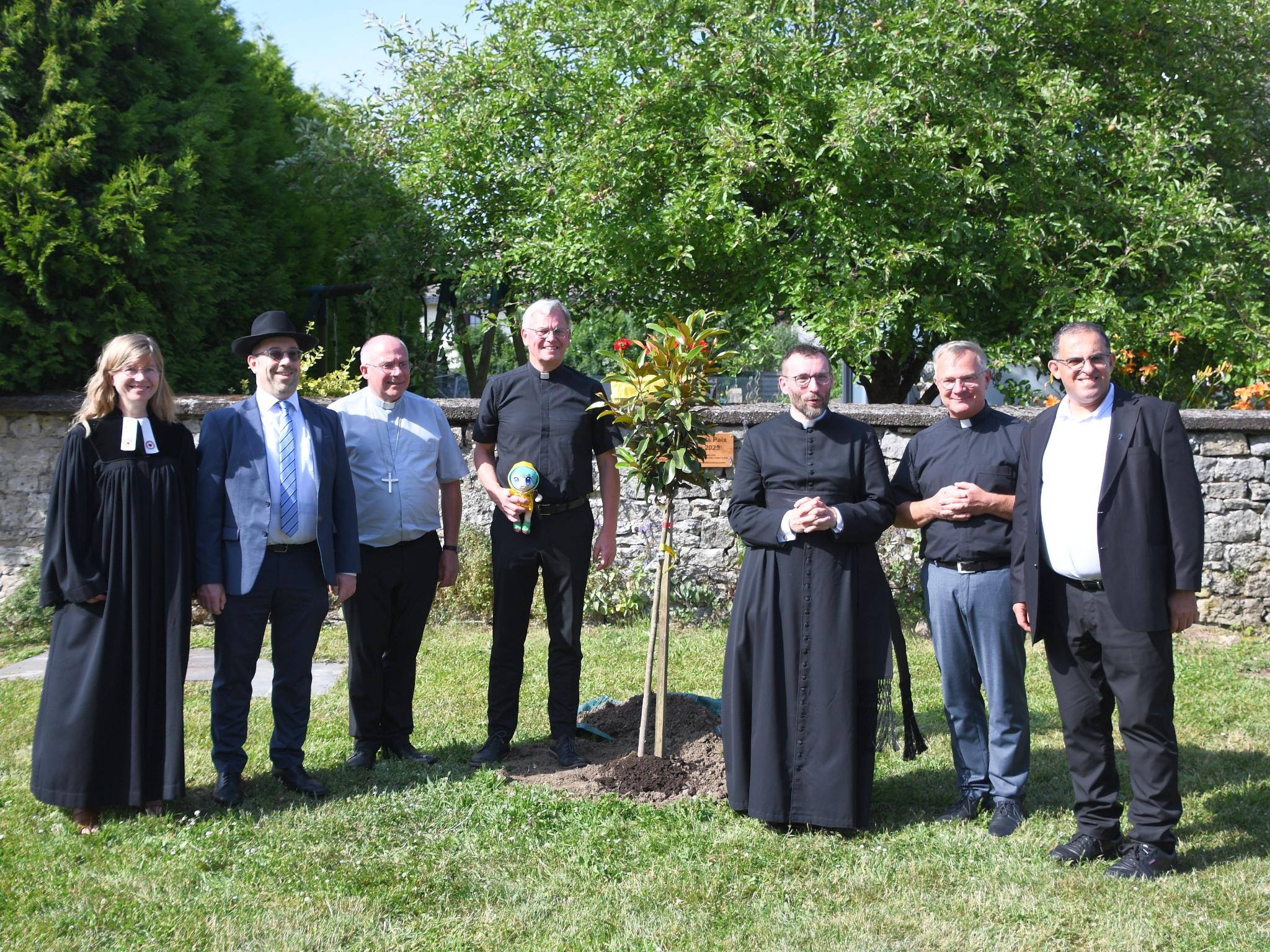 Cosima Hoffmann, Ariel Wertenschlag, Erzbischo Philippe Ballot, Generalvikar Ulrich von Plettenberg, David Chaudey, Markus Wirth und Samih Raad vor dem frisch gepflanzten Friedensbaum.