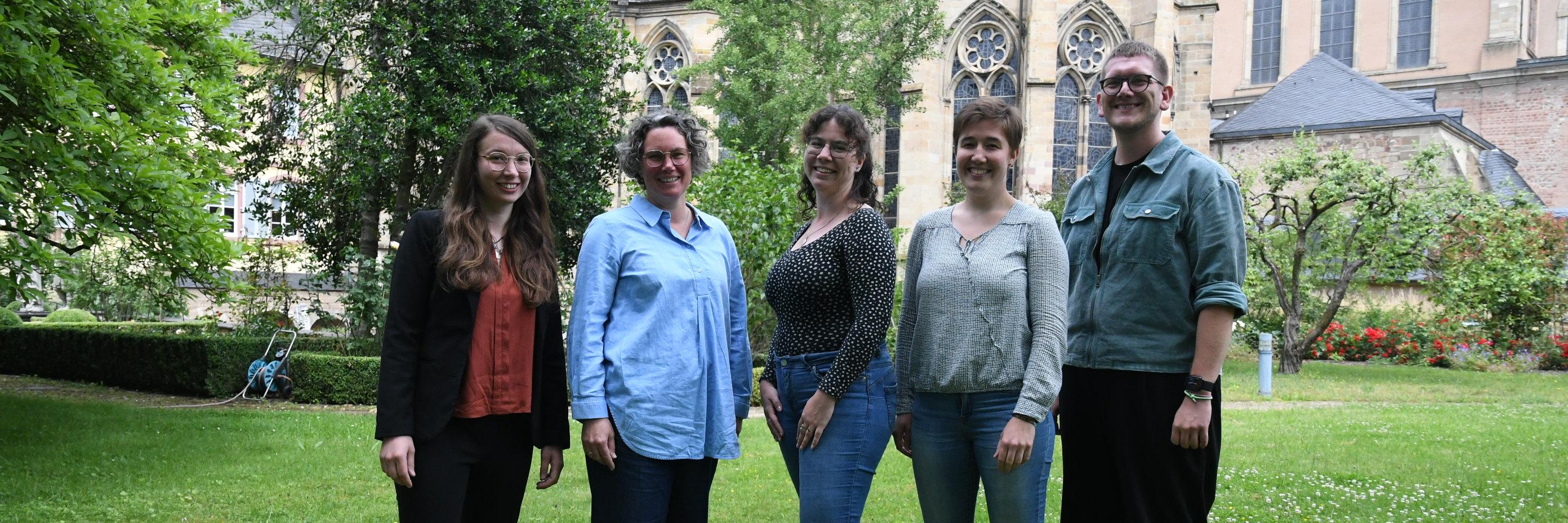 Vier Frauen und ein Mann stehen lächelnd im Grünen; im Hintergrund Liebfrauen