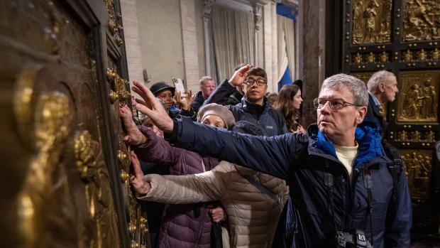 Pilger berühren  beim Durchschreiten die Heilige Pforte im Petersdom im Vatikan.