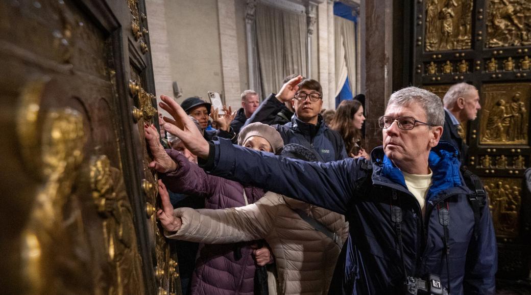 Pilger berühren  beim Durchschreiten die Heilige Pforte im Petersdom im Vatikan.