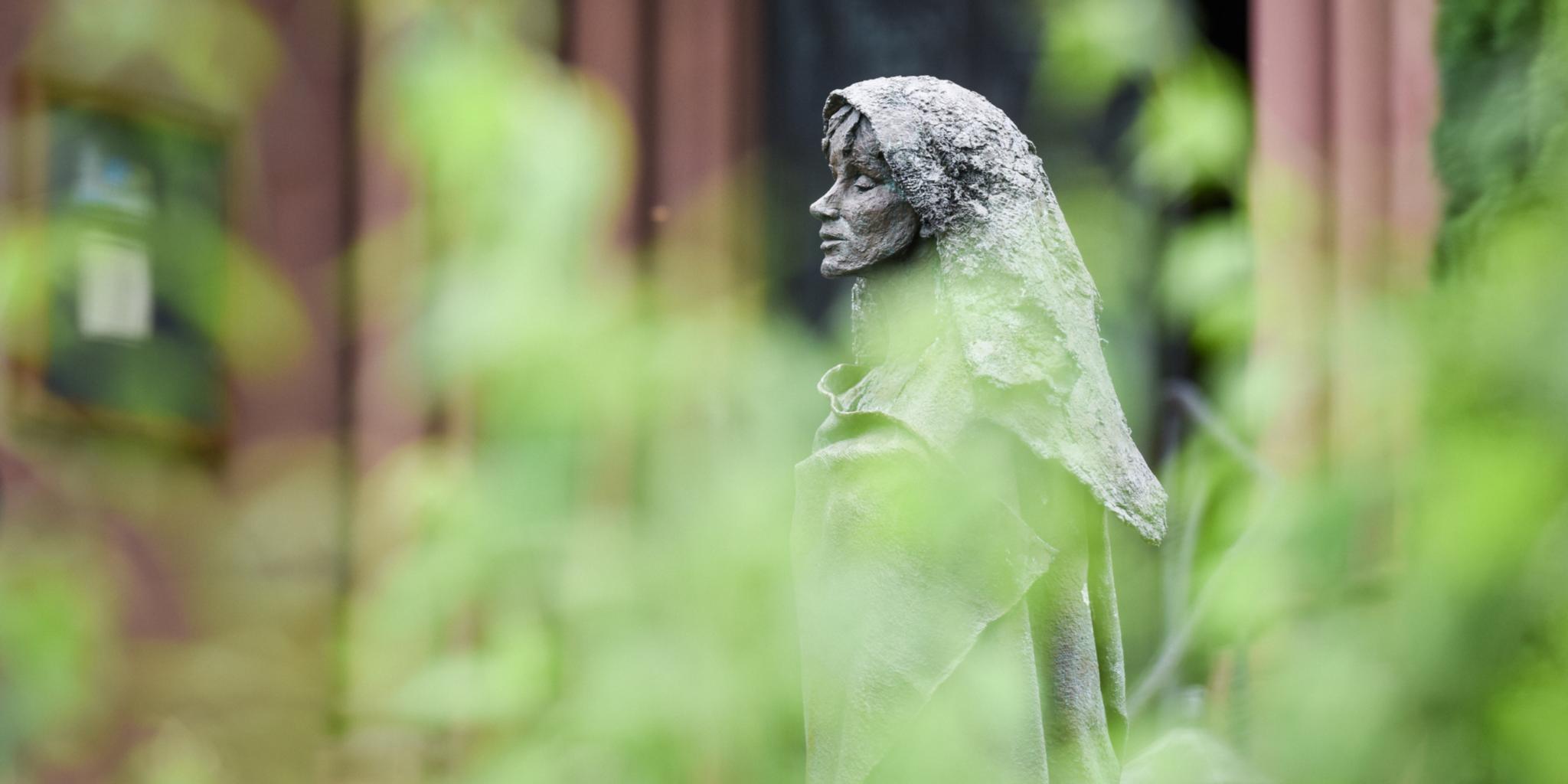 Eine Figur von Hildegard von Bingen steht im Klostergarten der Benediktinerinnenabtei Sankt Hildegard in Rüdesheim.