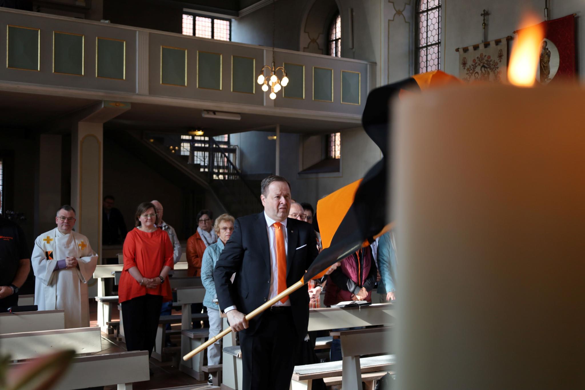 Eine Gruppe von Menschen zieht mit Fahnen in die Kirche ein