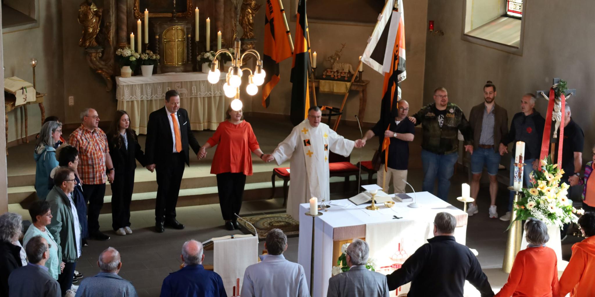 Menschen halten sich bei den Händen und bilden einen Kreis um den Altar