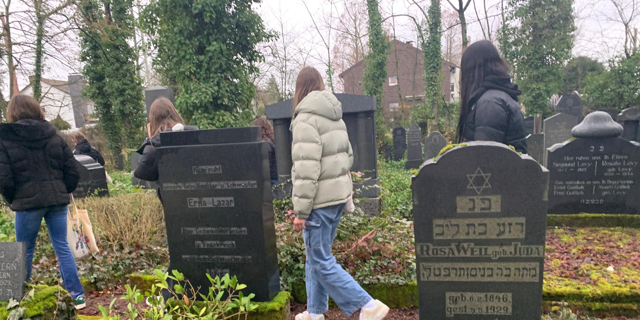 Schülerinnen und Schüler legen Steine auf jüdischen Gräbern in Saarlouis nieder.