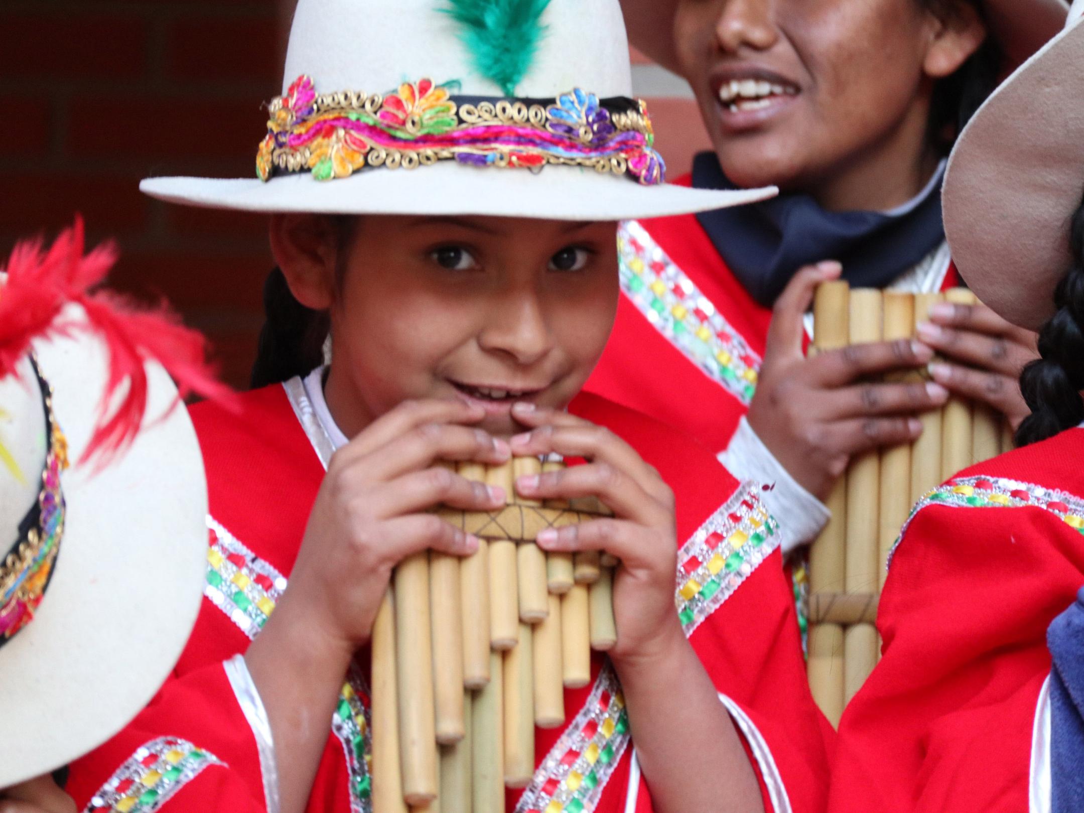 Bolivianisches Mädchen in traditioneller Tracht und mit Panflöte.