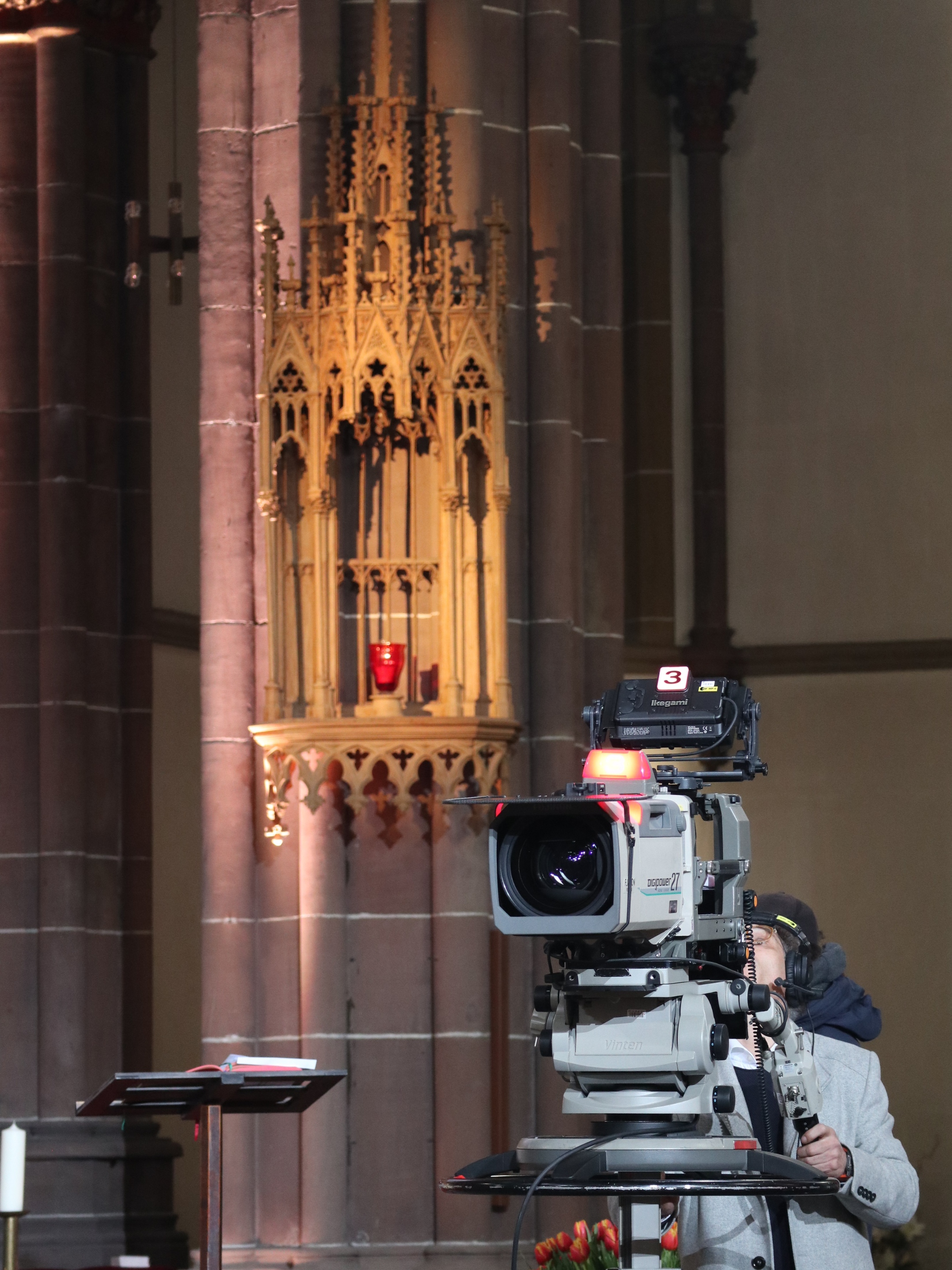 Eine große Fernsehkamera in einem Kirchenraum.