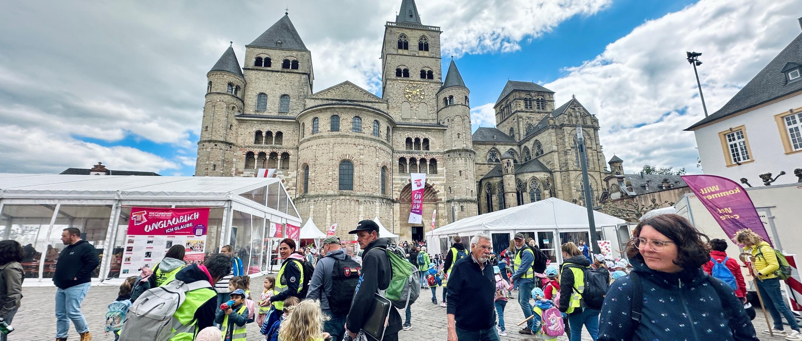 Man sieht den Trierer Dom, Zelte, Pavillions, Fahnen und viele Menschen, die auf dem Domfreihof sind im Rahmen der Heilig-Rock-Tage