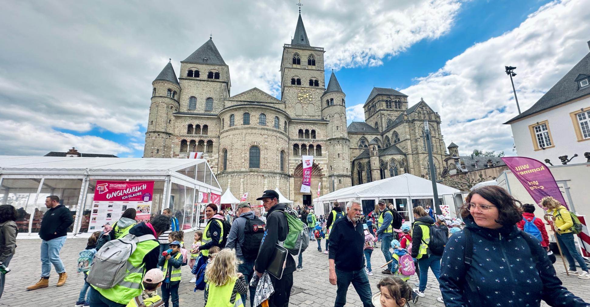 Man sieht den Trierer Dom, Zelte, Pavillions, Fahnen und viele Menschen, die auf dem Domfreihof sind im Rahmen der Heilig-Rock-Tage
