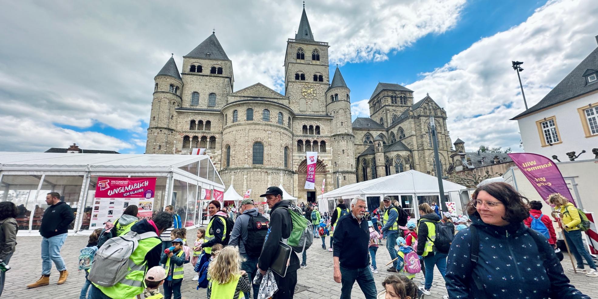 Man sieht den Trierer Dom, Zelte, Pavillions, Fahnen und viele Menschen, die auf dem Domfreihof sind im Rahmen der Heilig-Rock-Tage