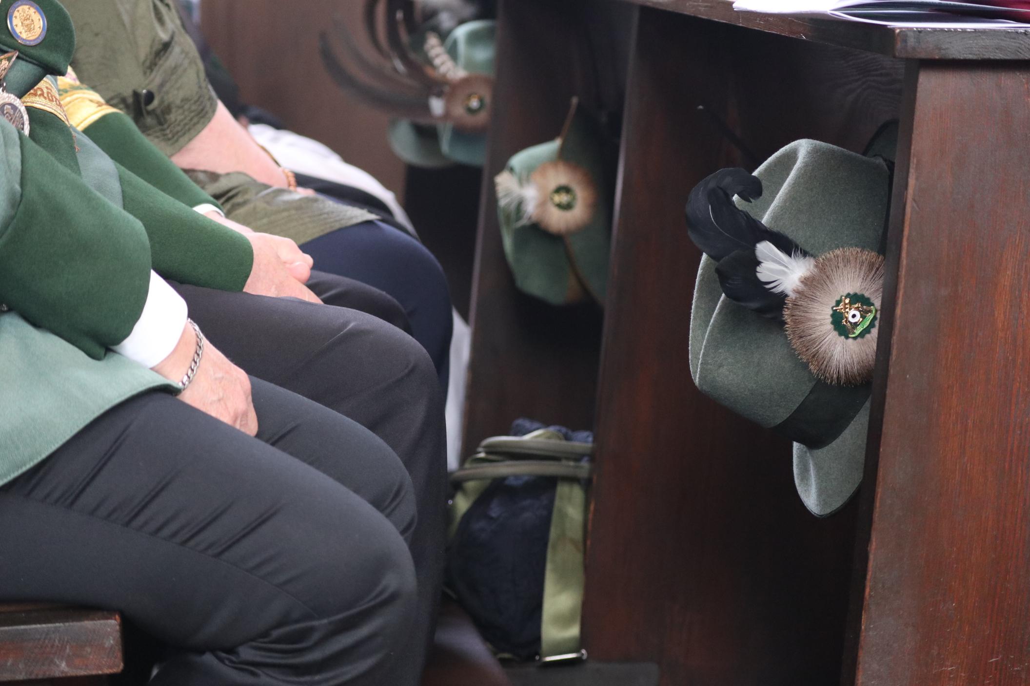 Schützenhüte hängen an einer Kirchenbank.