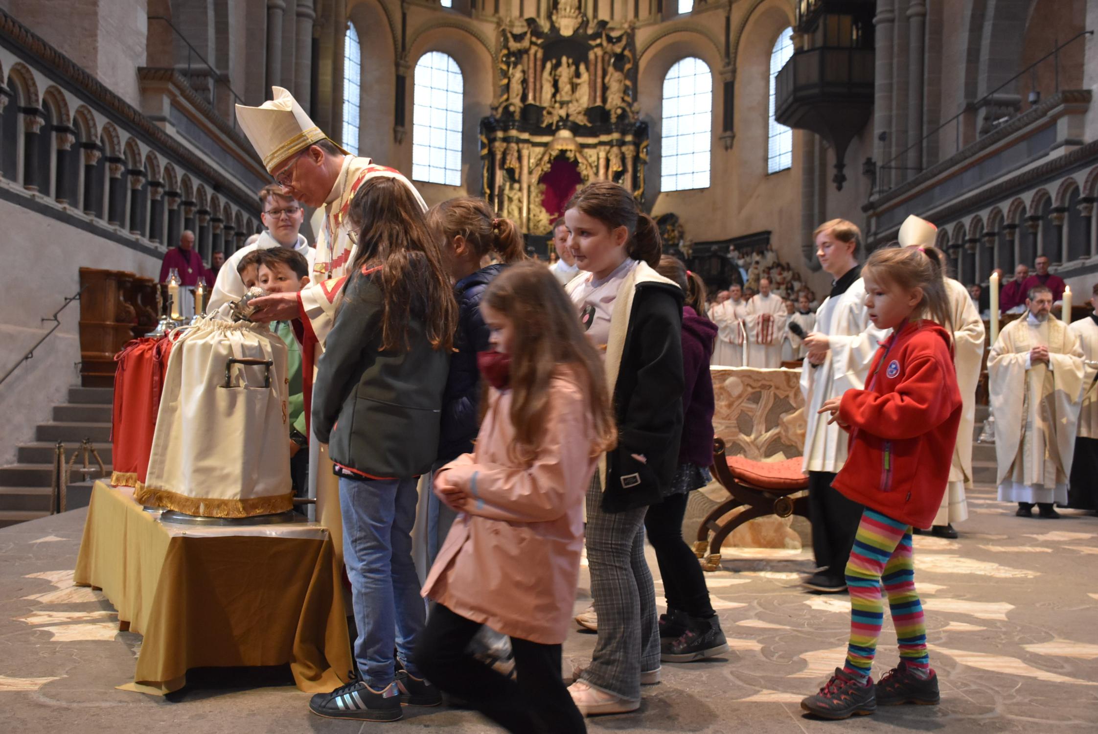 Kommunionkinder schauen aufmerksam zu, wie der Bischof dem Olivenöl Balsam und Duftstoffe für das Chrisamöl beimischt.