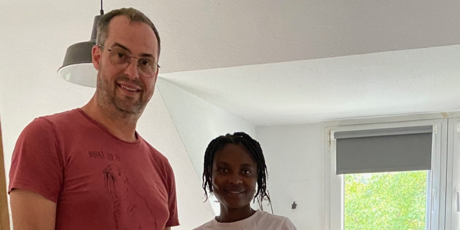 Ein Mann in rotem T-Shirt steht neben einer Frau. Beide lächeln.