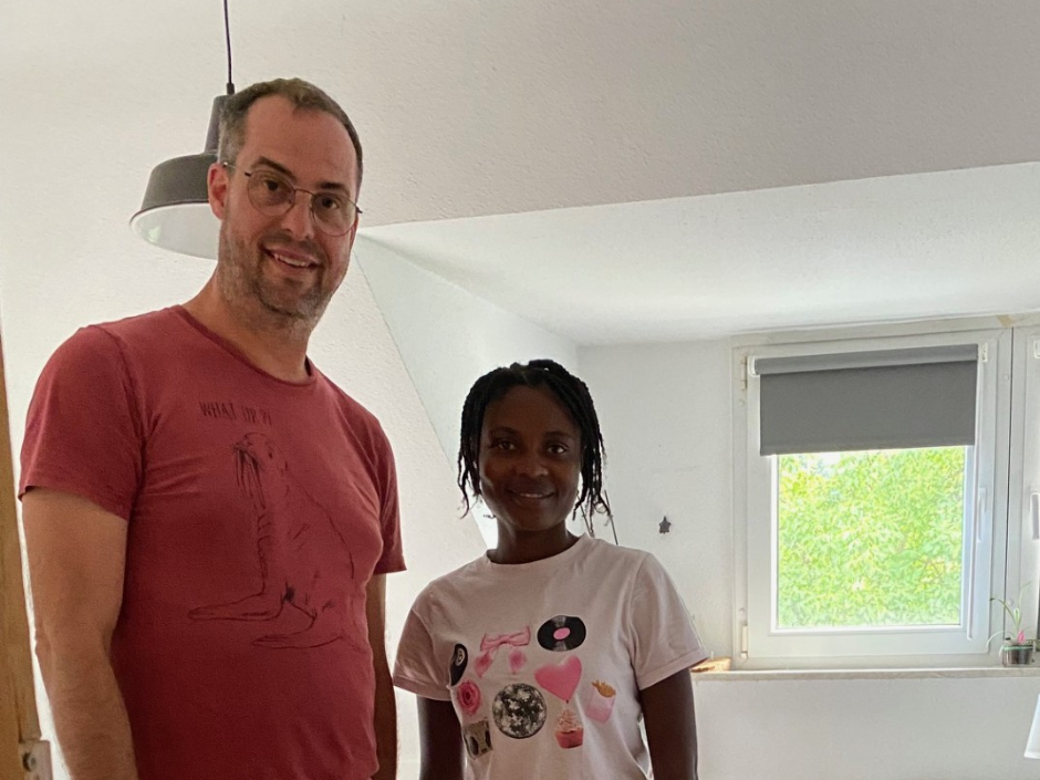 Ein Mann in rotem T-Shirt steht neben einer Frau. Beide lächeln.