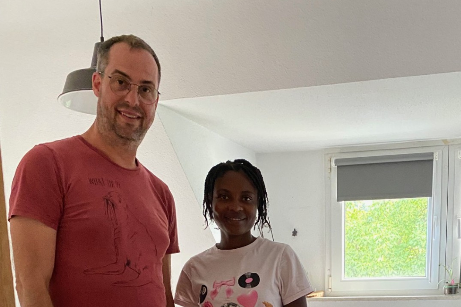 Ein Mann in rotem T-Shirt steht neben einer Frau. Beide lächeln.