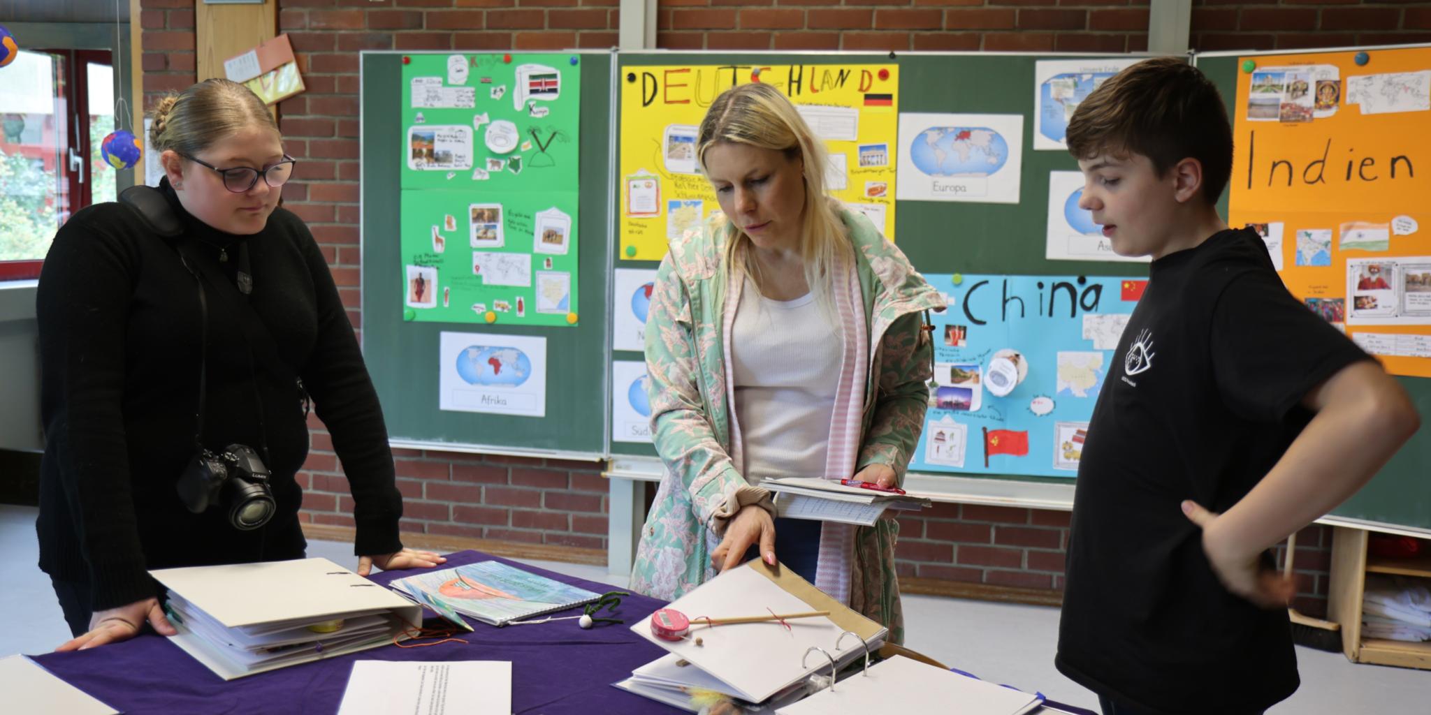 Die Schülerin Mary (rechts) und Schüler Kim (links) zeigen Kathrin Schmitt von der Trierischen Tonpost ihre Buch-Übersetzungen.