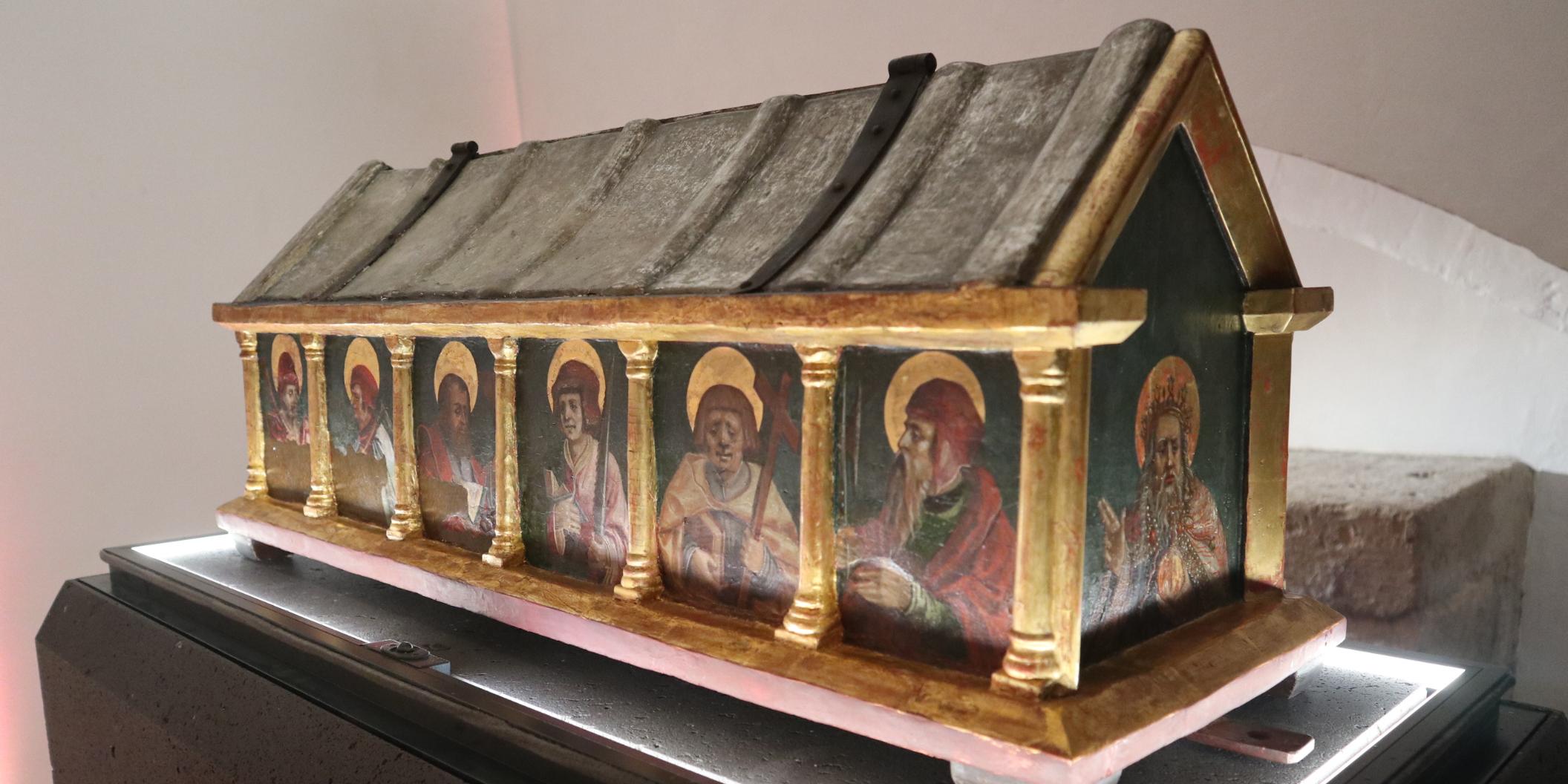 Eine kunstvollverzierte Holzkiste mit Heiligenfiguren daraufgemalt.
