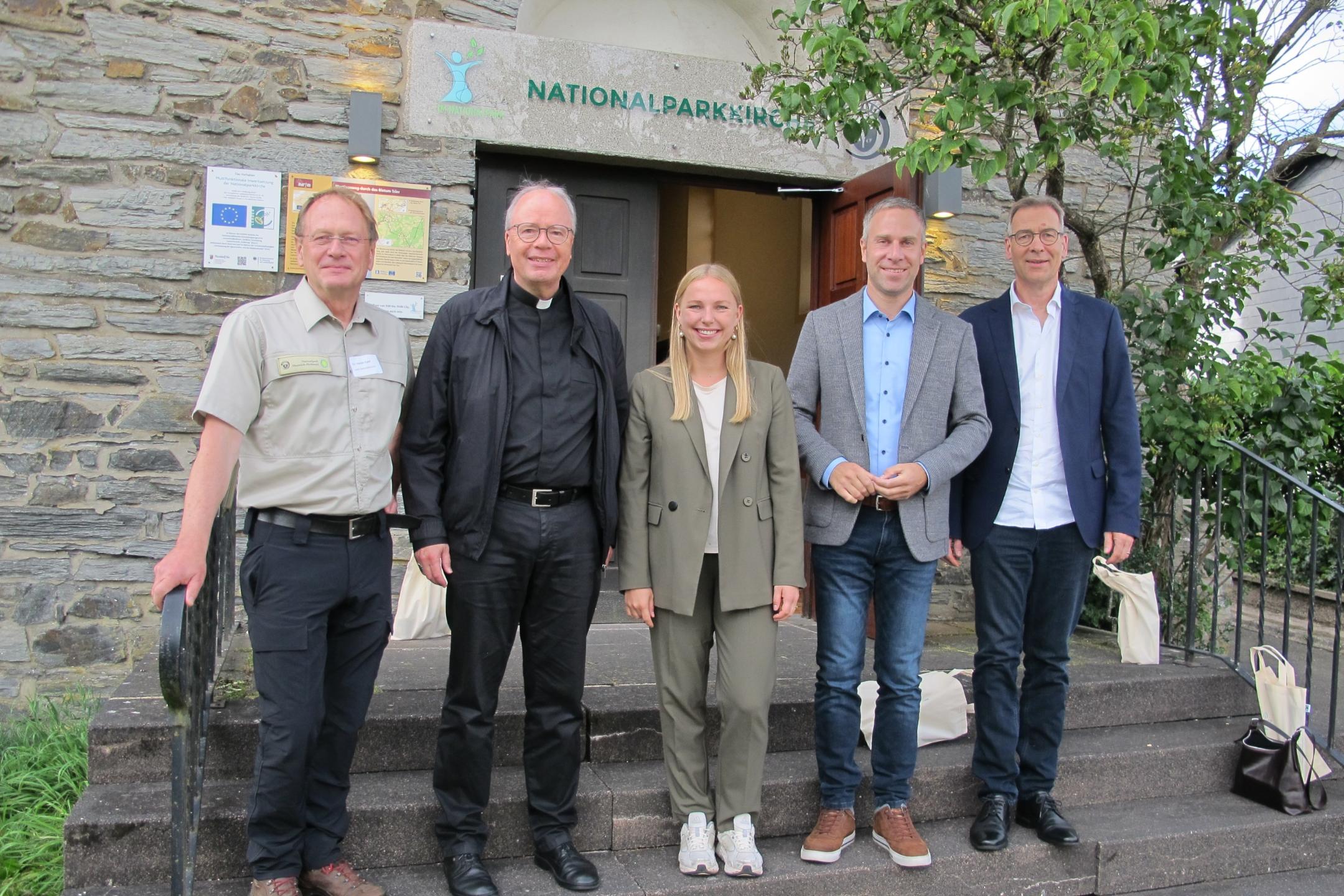 Dr. Harald Egidi, Bischof Dr. Stephan Ackermann, Kira Braun, Nico Steinbach und Superintendent Dr. Jörg Weber stehen vor dem Eingang zur Kirche von Muhl