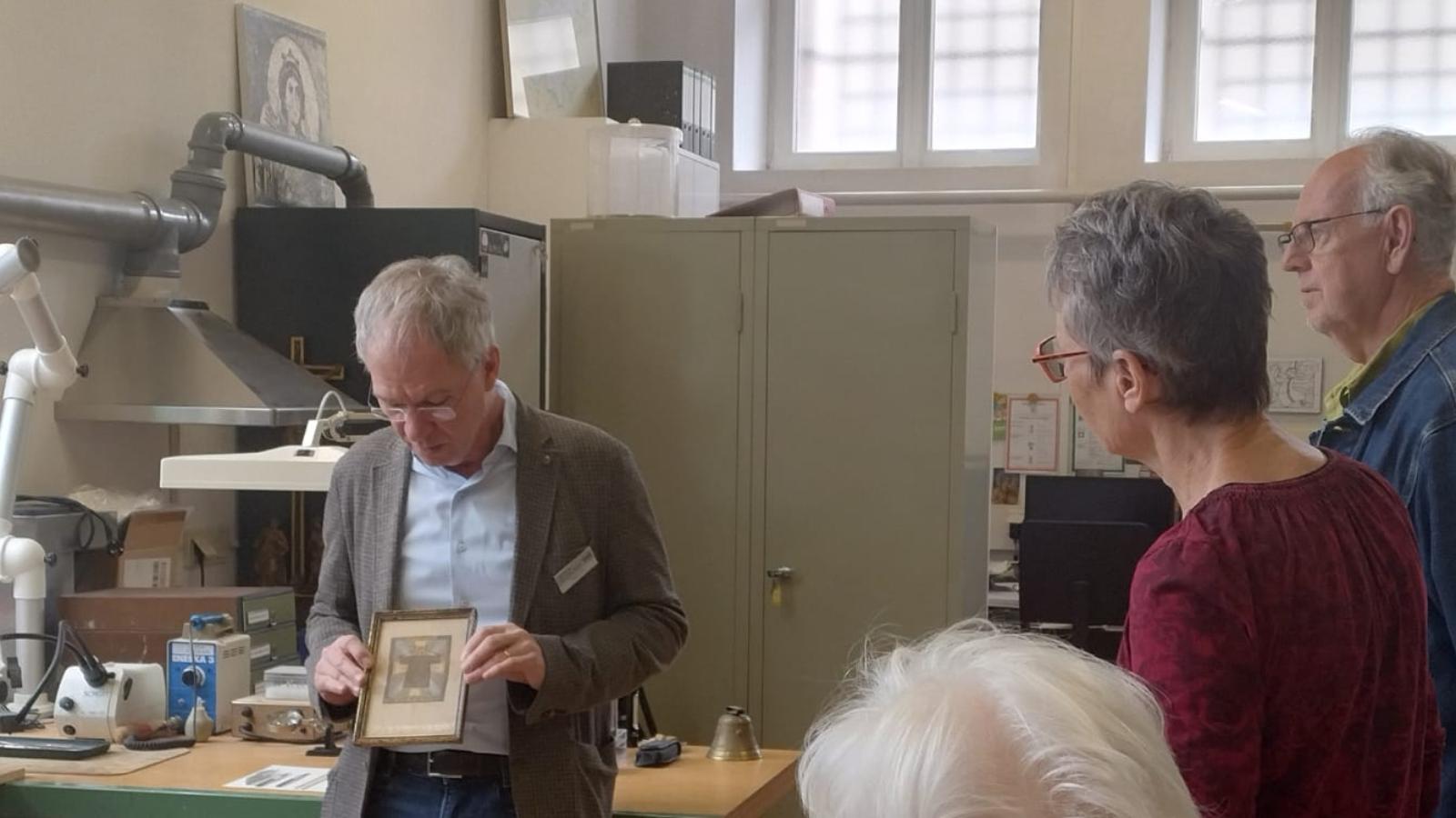 Der stellvertretende Museumsleiter und Restaurator Stefan Schu zeigt Gästen ein gerahmtes Bild.