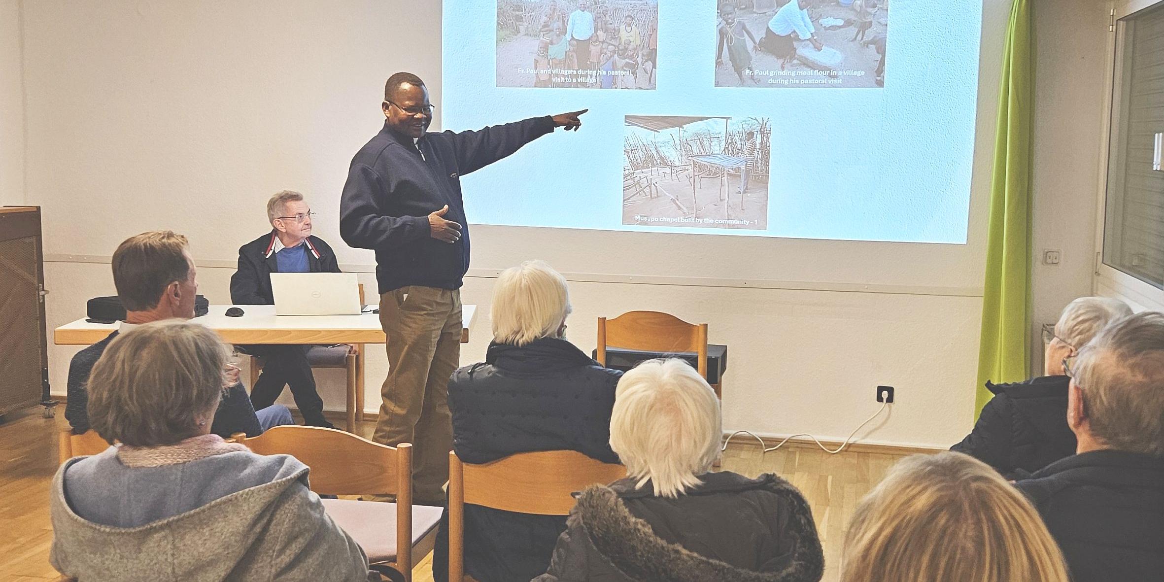 Generalvikar Ngole zeigt bei seinem Vortrag Bilder auf einer Leinwand.
