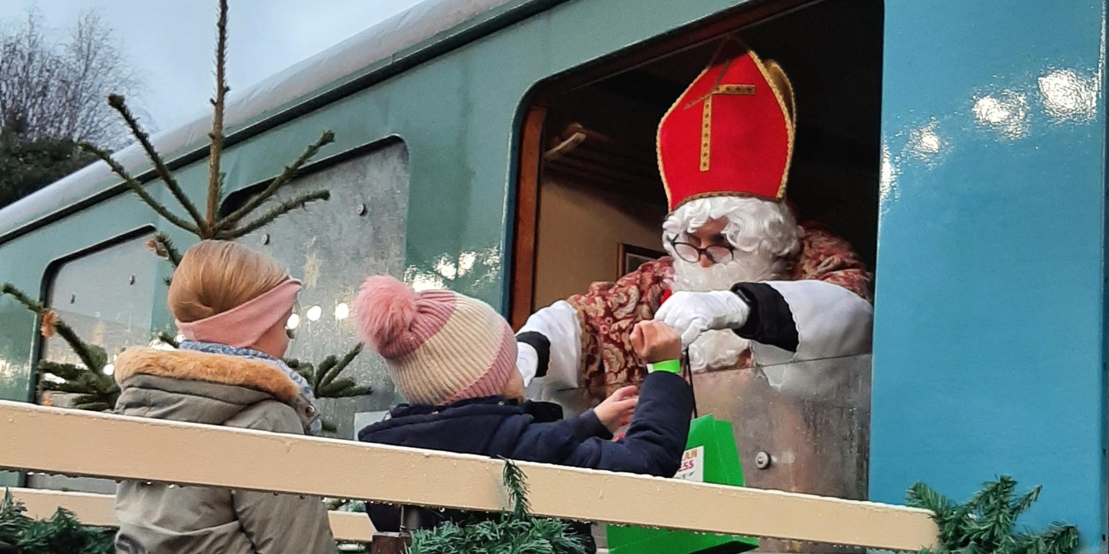Niklaus verteilt Süßigkeiten aus einem Bahnfenster heraus.
