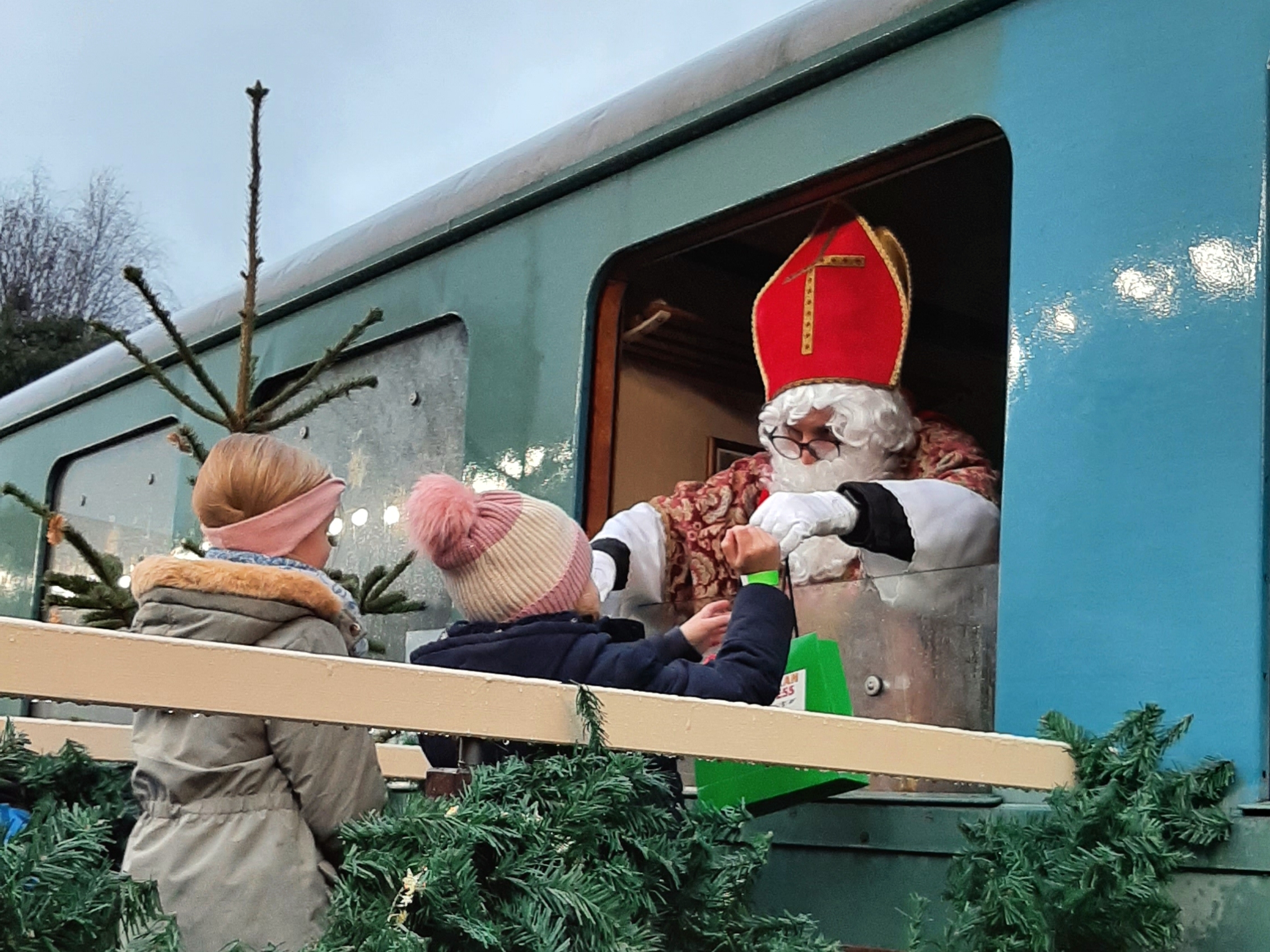 Niklaus verteilt Süßigkeiten aus einem Bahnfenster heraus.