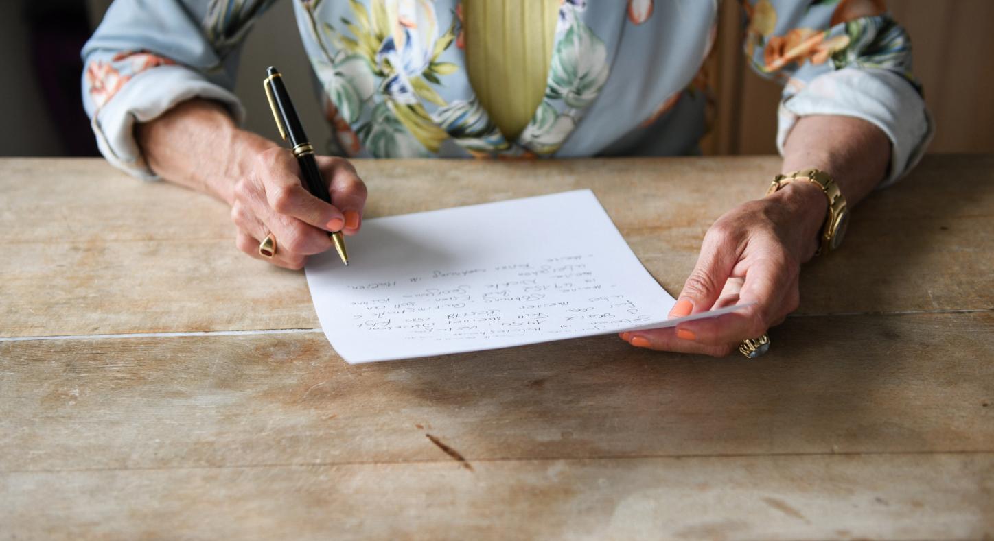 Eine Frau beim verfassen ihres handschriftlichen letzten Willens.