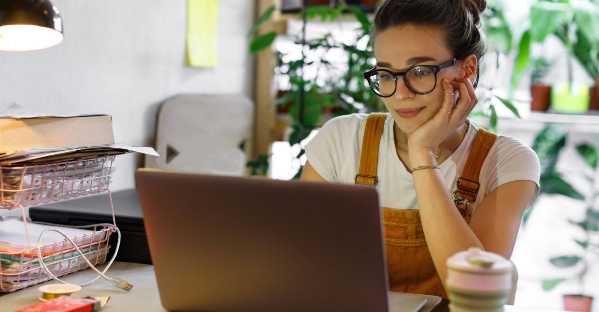 Eine Frau blickt zufrieden auf den Bildschirm ihres Notebooks.