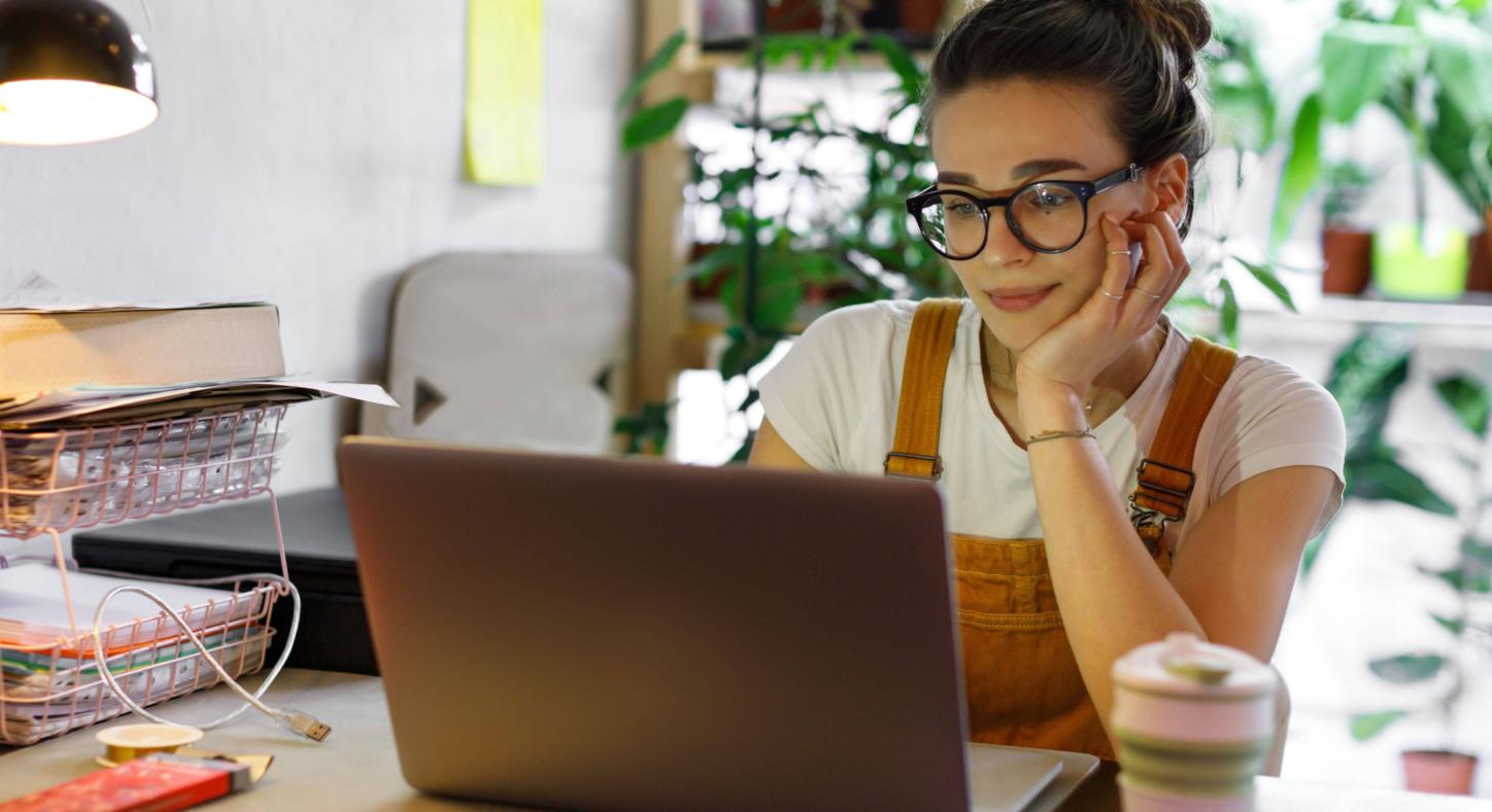 Eine Frau blickt zufrieden auf den Bildschirm ihres Notebooks.