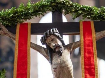 Jesus hängt am Kreuz, umrahmt von Palmzweigen