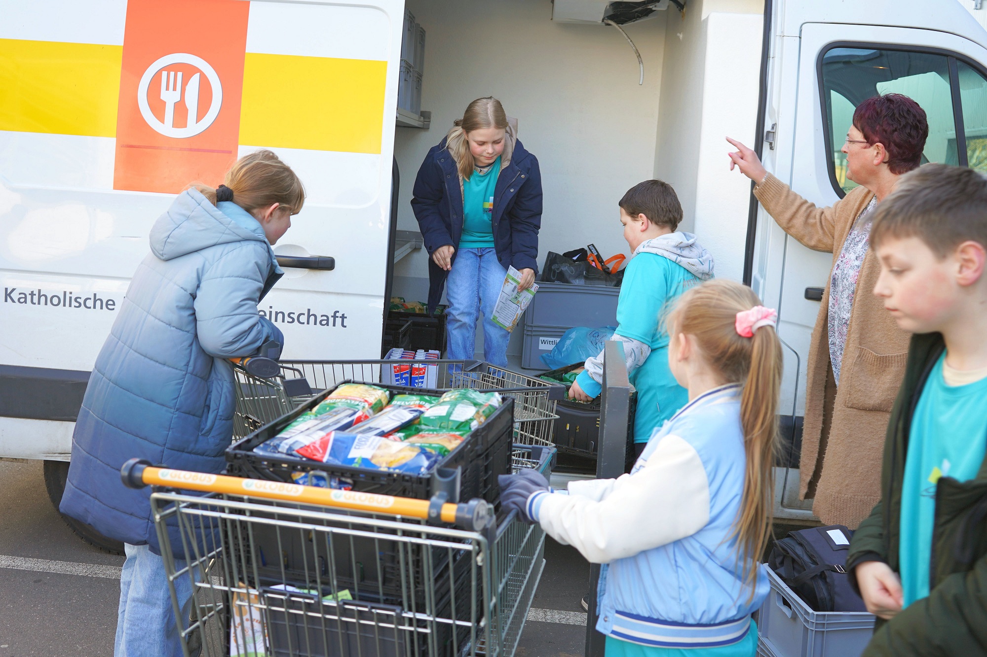 Schülerinnen und Schüler aus Wittlich laden gesammelte Lebensmittel in den „Tafel“-Transporter.
