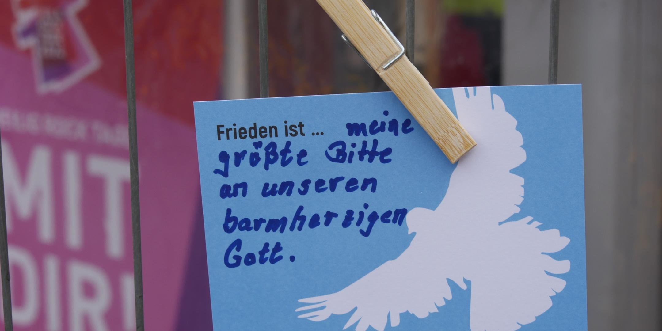 Am Zaun neben dem Infozelt hängen die Friedens-Postkarten.