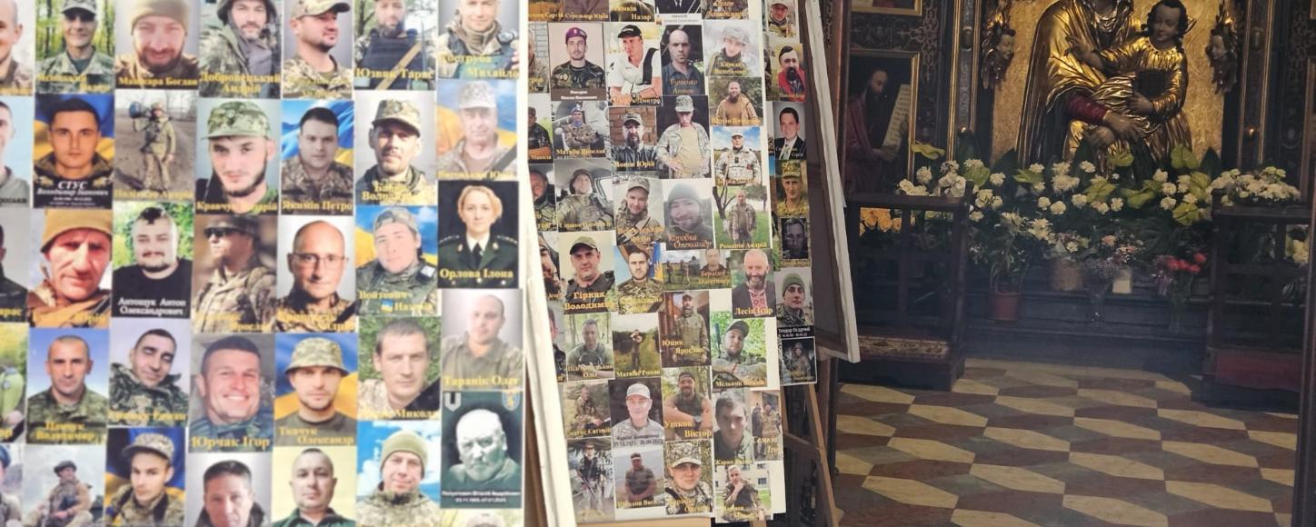 In einer Kirche stehen mehrere Staffeleien mit Fotos von Soldaten. Im Hintergrund befindet sich ein Altar mit einer goldenen Marienstatue und Blumenschmuck.