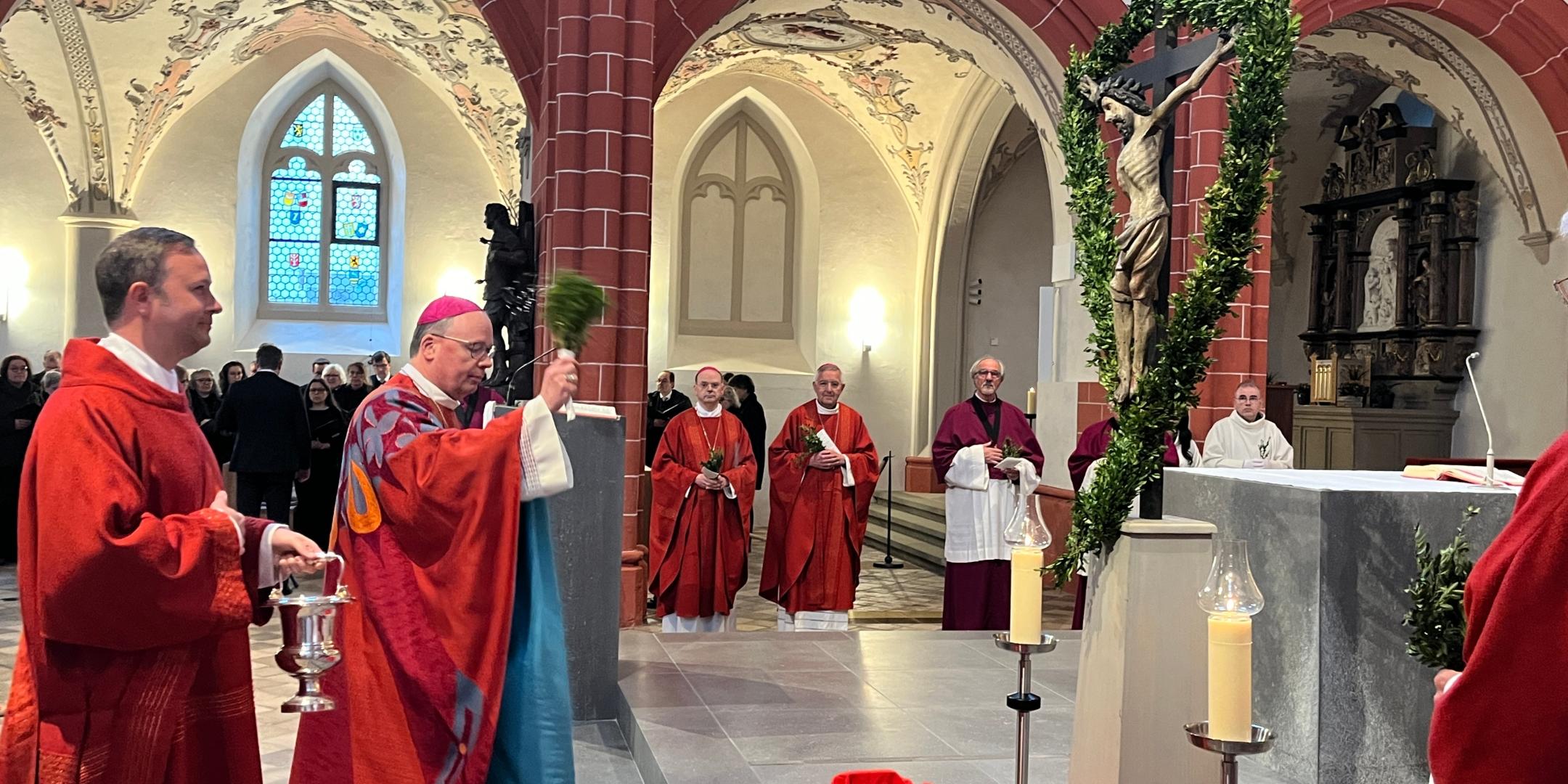 Bischof Ackermann segnet in der Bürgerkirche St. Gangolf die Palmzweige.