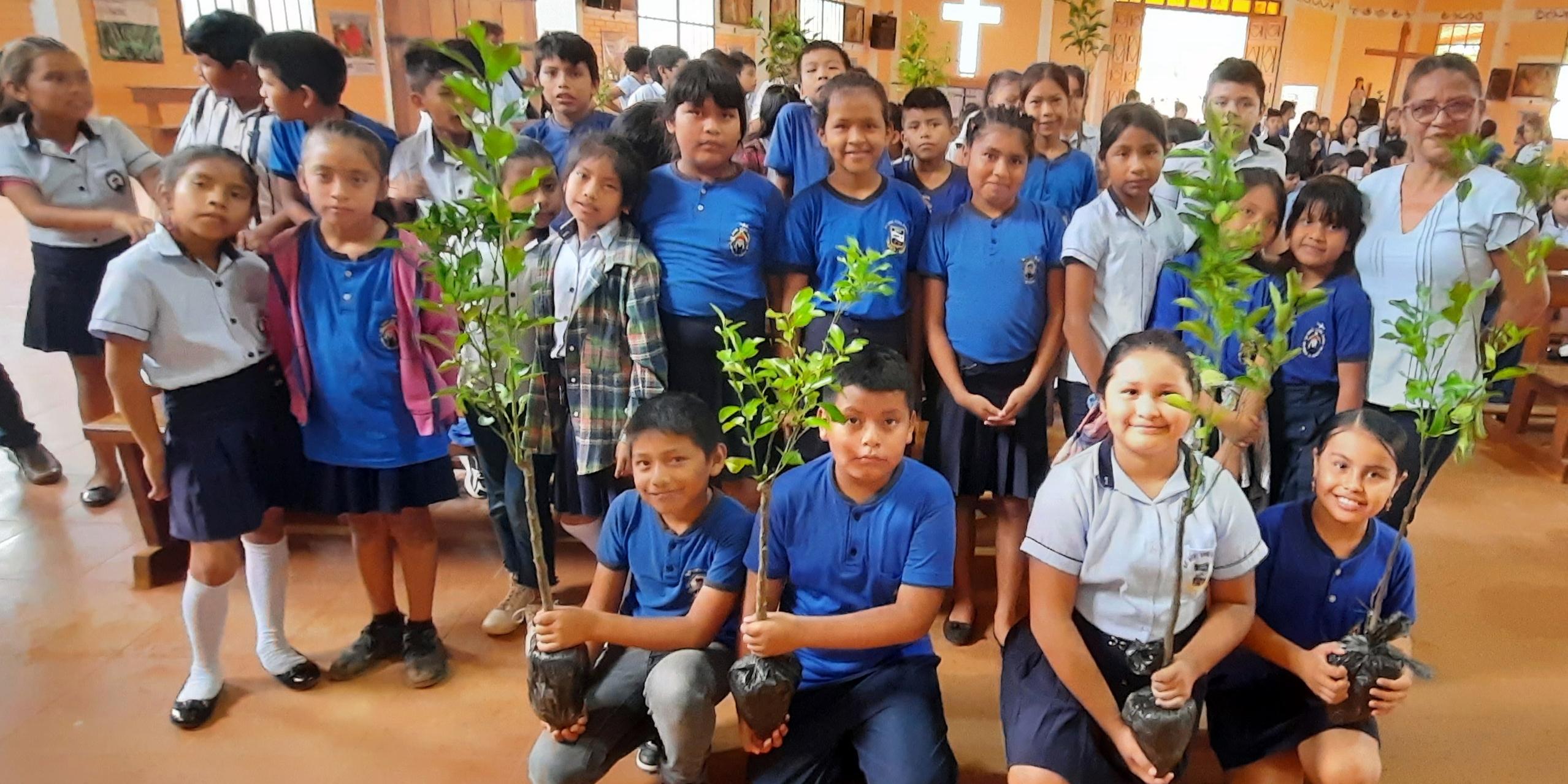 Ein Gruppenfoto einer Gruppe von Kindern mit Baumsetzlingen in einer Kirche in Bolivien, welche danach bei einer Aktion gepflanzt wurden.