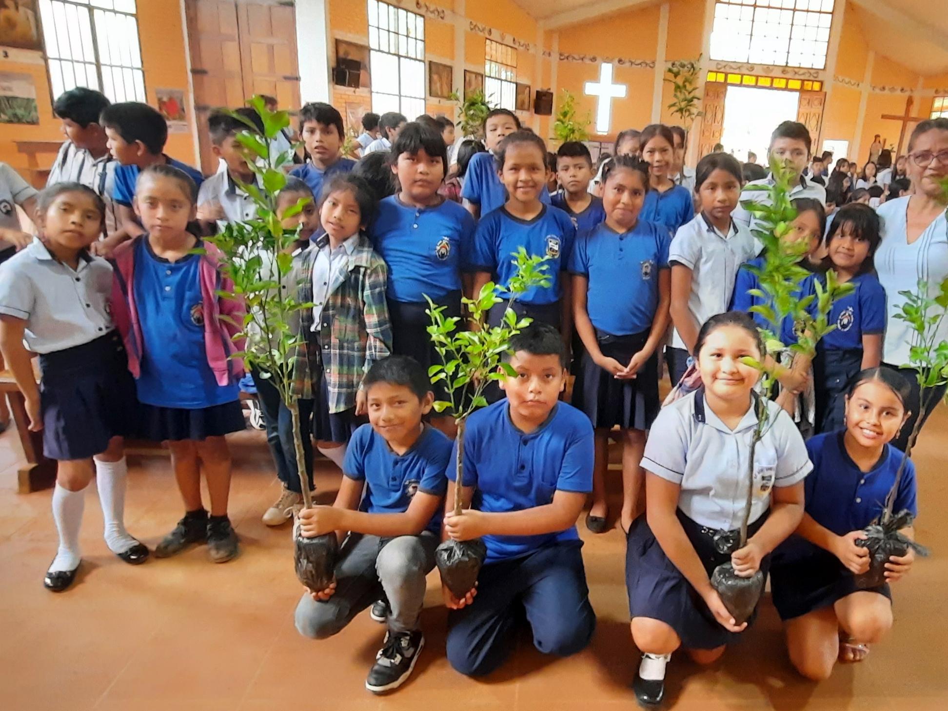Ein Gruppenfoto einer Gruppe von Kindern mit Baumsetzlingen in einer Kirche in Bolivien, welche danach bei einer Aktion gepflanzt wurden.
