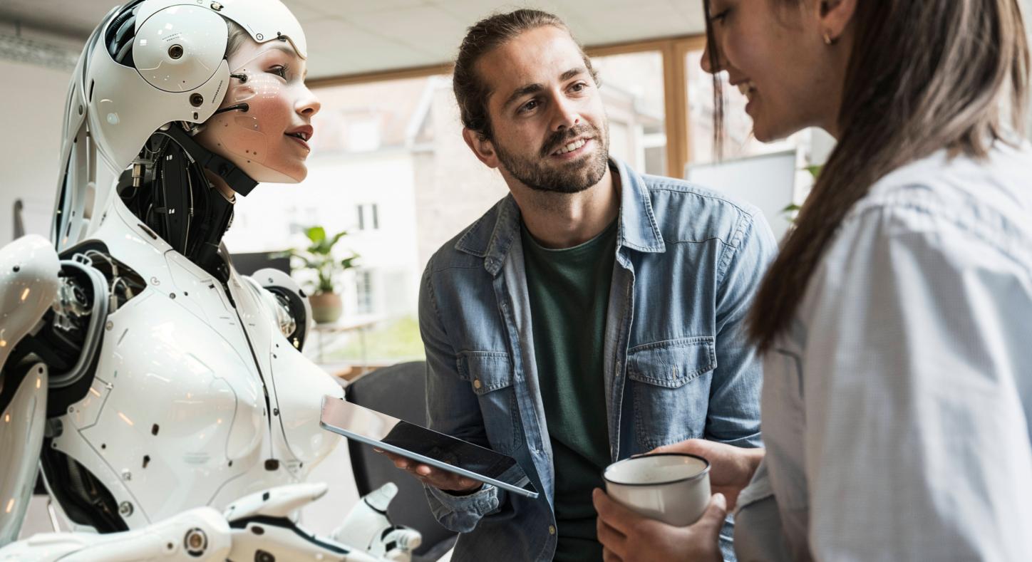 Ein menschenähnlicher Roboter, ein Mann und eine Frau im Gespräch.