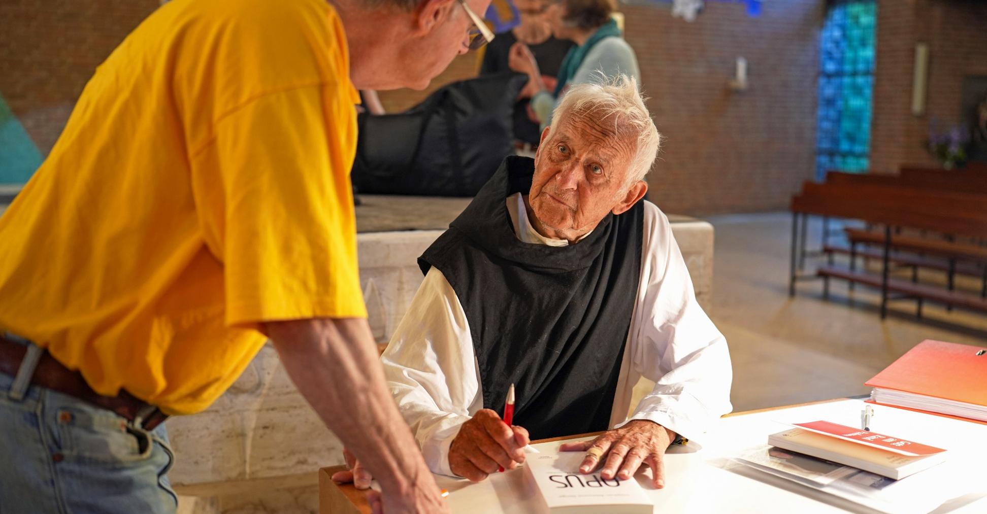 Pater Stephan signiert sein neuestes Buch mit dem Titel „Opus“.